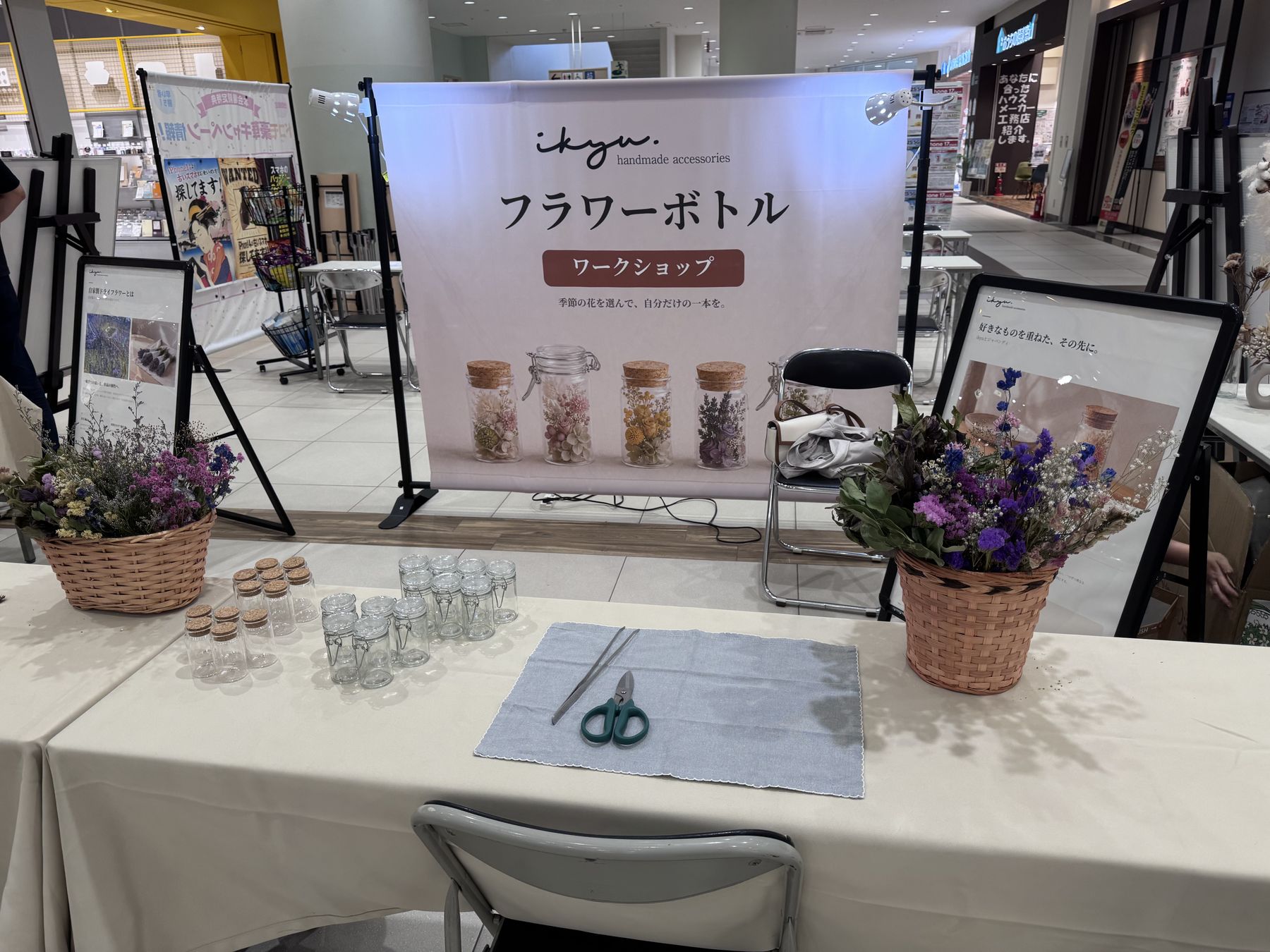 アリオ札幌のフラワーボトルワークショップのブース全景。バナーと花材が並ぶテーブル
