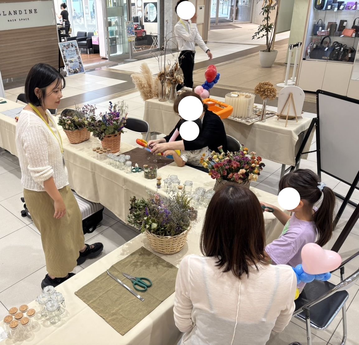 テーブルを囲んで花材を選びながら、フラワーボトルを制作する参加者たち。