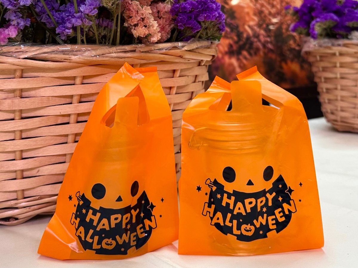 ドライフラワーを盛ったかごの前に、完成したフラワーボトルを入れたハロウィン柄のオレンジ色の袋が二つ