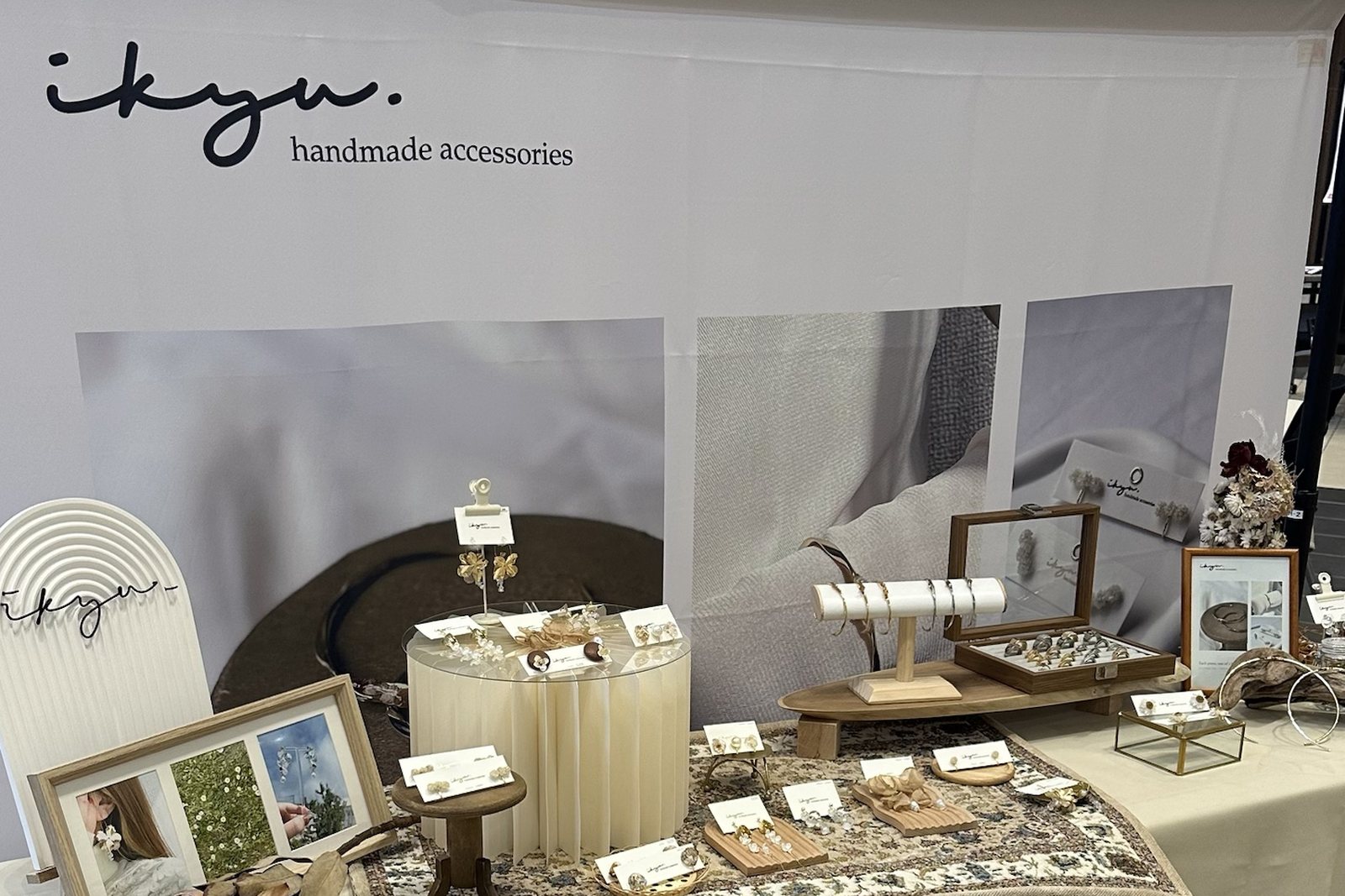 ikyuのロゴ入りバナーを背に、ハンドメイドアクセサリーが並ぶ展示テーブル。エルフィンコートのブースにて